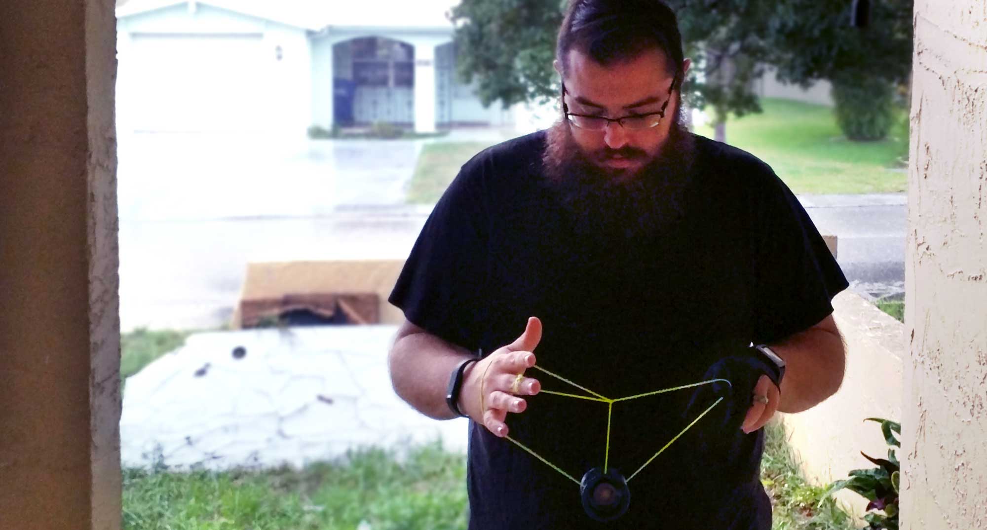 Steven yoyoing outdoors, the yoyo is sitting in a nest of strings